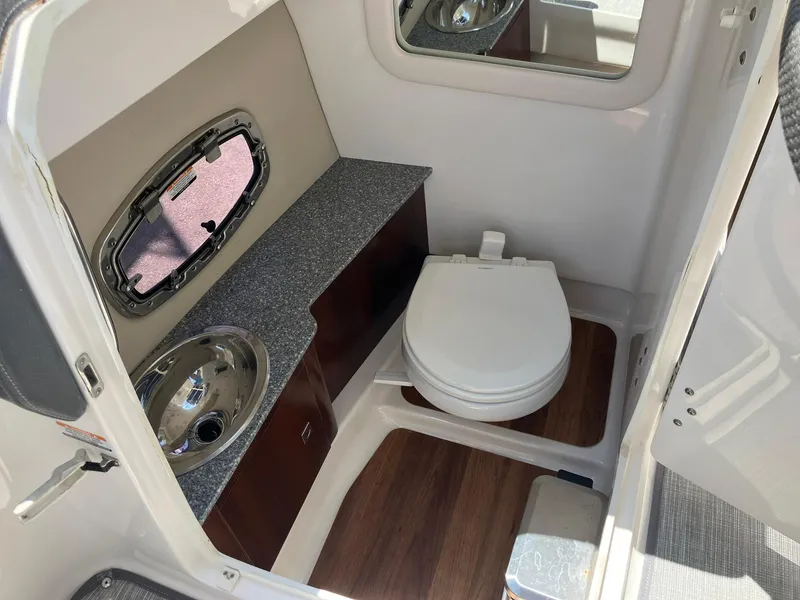 Slide: The Image of 2017 Chaparral 257 SSX boat bathroom with sink, toilet, and wood flooring. - 24