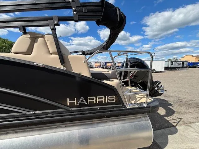 Slide: The Image of 2025 Harris CRUISER 230 SLDH pontoon boat, black exterior, parked outdoors under blue sky. - 3