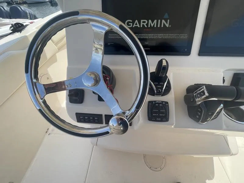 Slide: The Image of Steering wheel and controls of 2024 Grady-White 306 CANYON boat with Garmin display. - 11