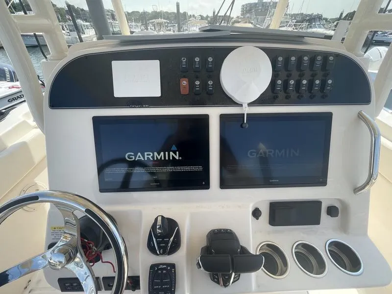 Slide: The Image of 2024 Grady-White 306 CANYON boat dashboard with Garmin navigation displays and controls. - 8