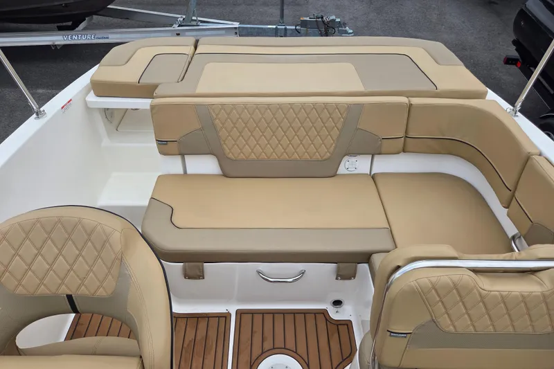 Slide: The Image of 2024 Bayliner VR5 boat interior with tan cushioned seating and wood accents. - 12