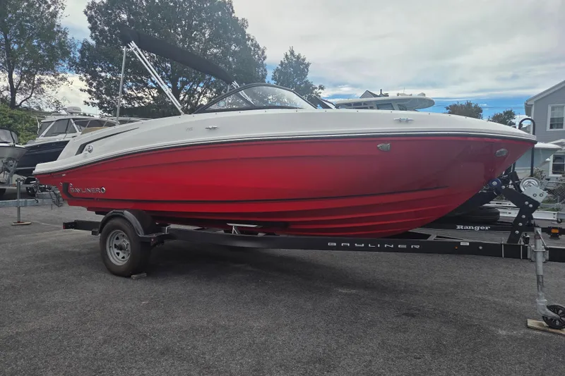 The Image of 2024 Bayliner VR5 Bowrider I/O with red hull on trailer, parked outdoors. - 2