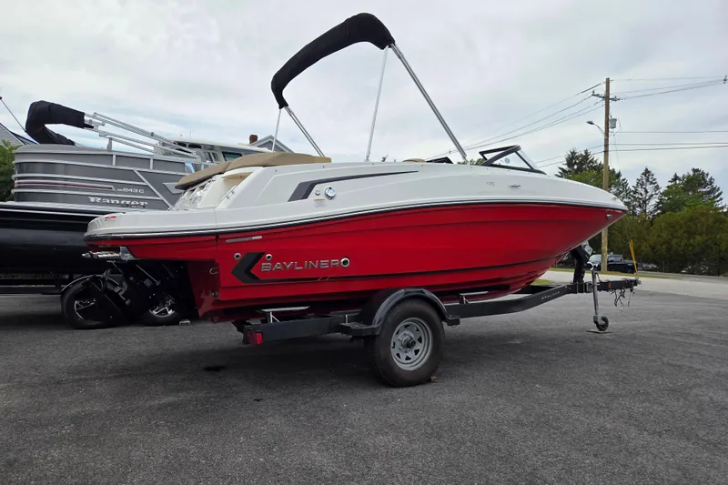 Slide: The Image of 2024 Bayliner VR5 boat with red hull on a trailer, parked outdoors. - 4