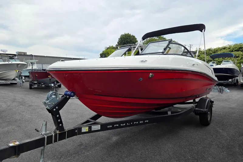 Slide: The Image of 2024 Bayliner VR5 boat with red hull on trailer, parked outdoors. - 7