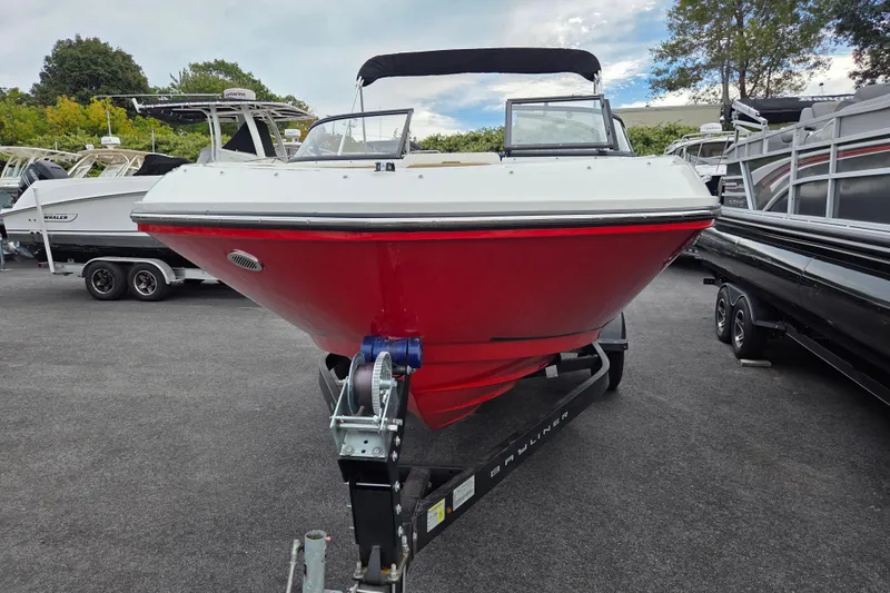Slide: The Image of 2024 Bayliner VR5 Bowrider I/O in red, parked on a trailer in a marina. - 8