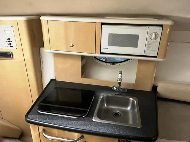 Slide: The Image of 2001 Maxum 2700 SCR boat kitchenette with sink, microwave, and storage cabinets. - 14