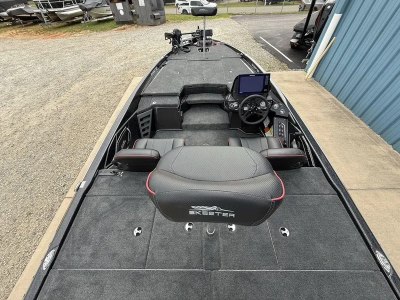 Slide: The Image of 2025 Skeeter ZXR20 boat interior with steering console and seating, parked outdoors. - 25