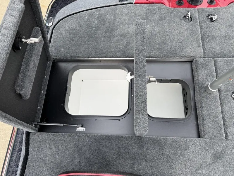 Slide: The Image of 2025 Skeeter ZXR20 boat storage compartments with gray carpeted interior. - 28