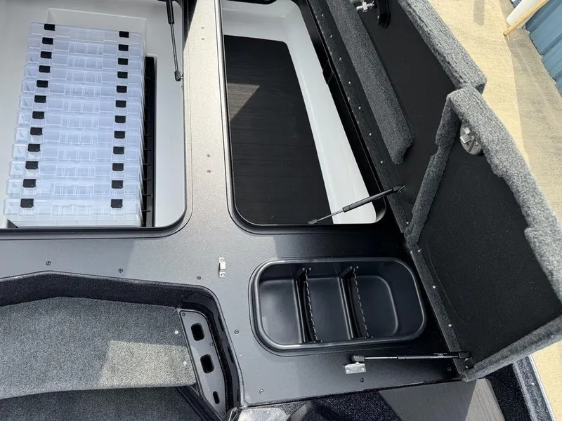 Slide: The Image of 2025 Skeeter ZXR20 boat storage compartments with organized tackle boxes and carpeted lids. - 9