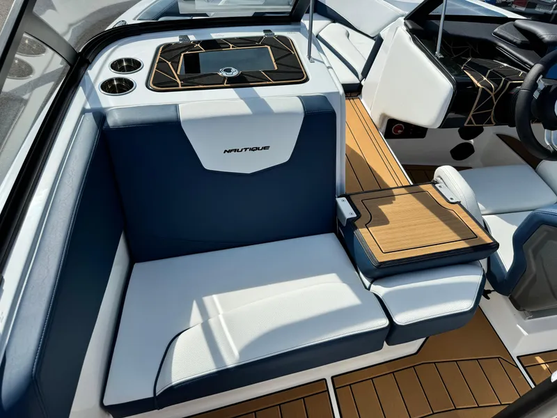 Slide: The Image of 2025 Nautique Ski 200 interior with blue and white seating, teak accents, and modern dashboard. - 17