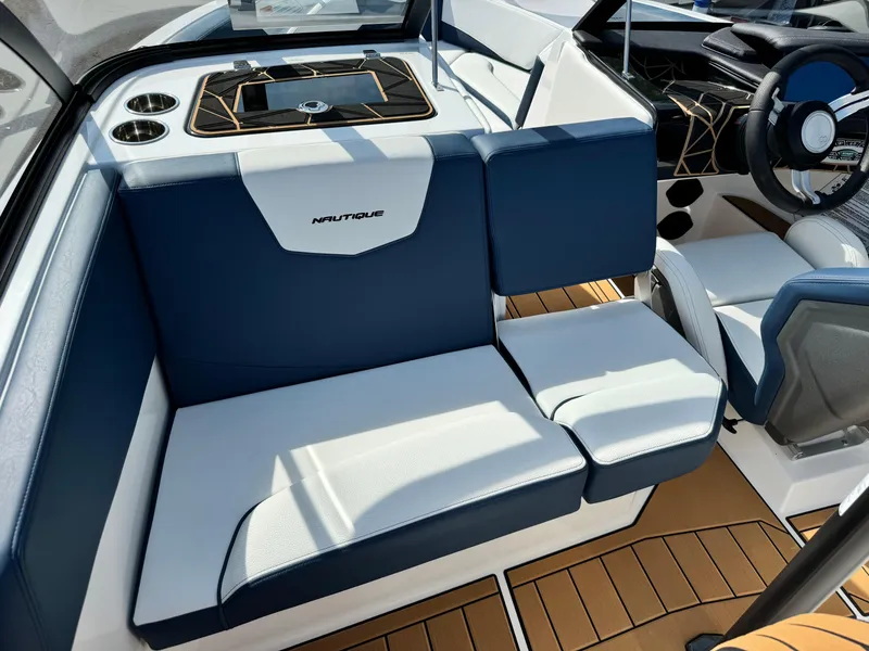Slide: The Image of 2025 Nautique Ski 200 interior with blue and white seating, modern dashboard, and teak flooring. - 18