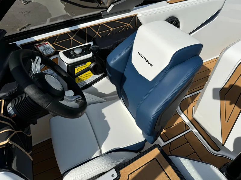 Slide: The Image of 2025 Nautique Ski 200 interior with blue and white seating and modern dashboard. - 27