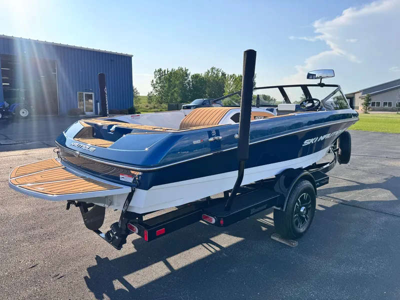 Slide: The Image of 2025 Nautique Ski 200 boat on trailer, parked outdoors under clear sky. - 3