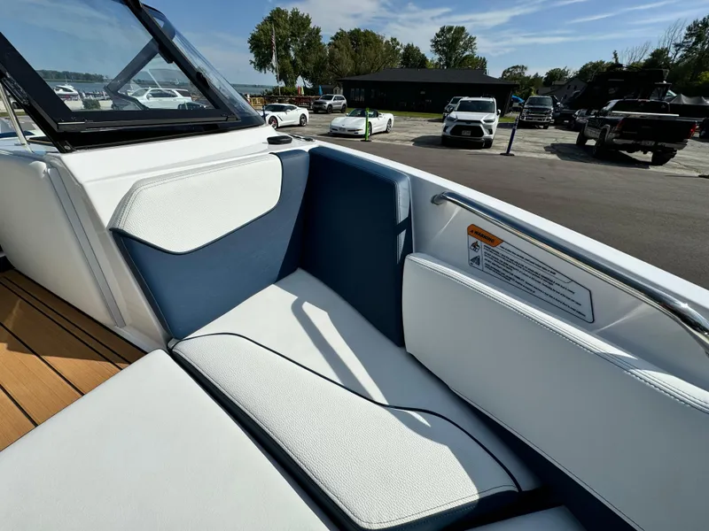 Slide: The Image of 2025 Nautique Ski 200 boat interior with white and blue seating, parked outdoors. - 35