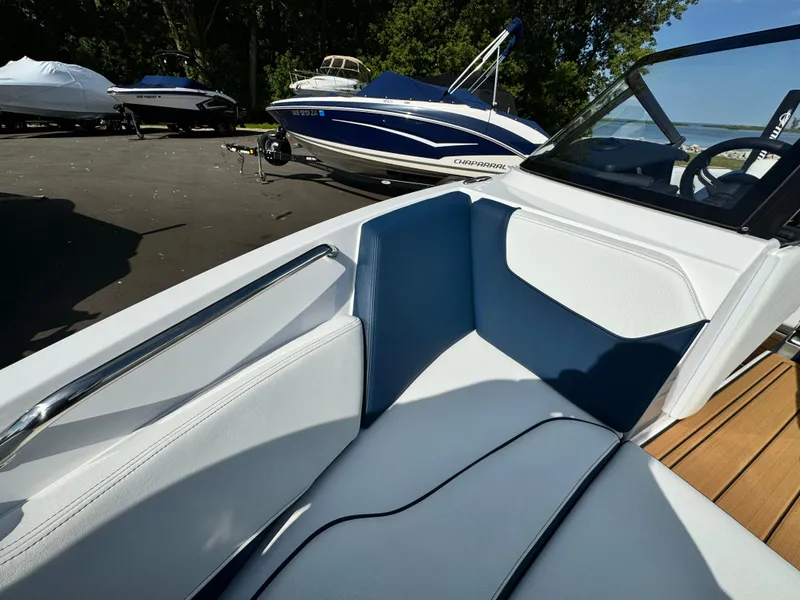 Slide: The Image of 2025 Nautique Ski 200 boat interior with blue and white seating, parked near other boats. - 36