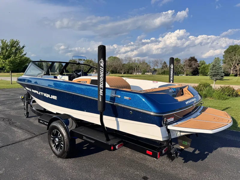 Slide: The Image of 2025 Nautique Ski 200 boat on trailer, blue and white, parked outdoors. - 5