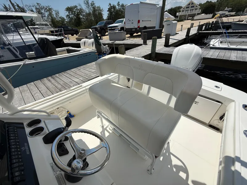 Slide: The Image of 2018 Regulator 23 boat interior with steering wheel and seating at a marina dock. - 13