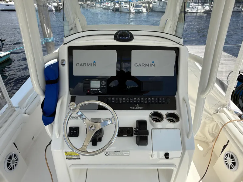 Slide: The Image of 2018 Regulator 23 boat helm with Garmin navigation system and steering wheel. - 16