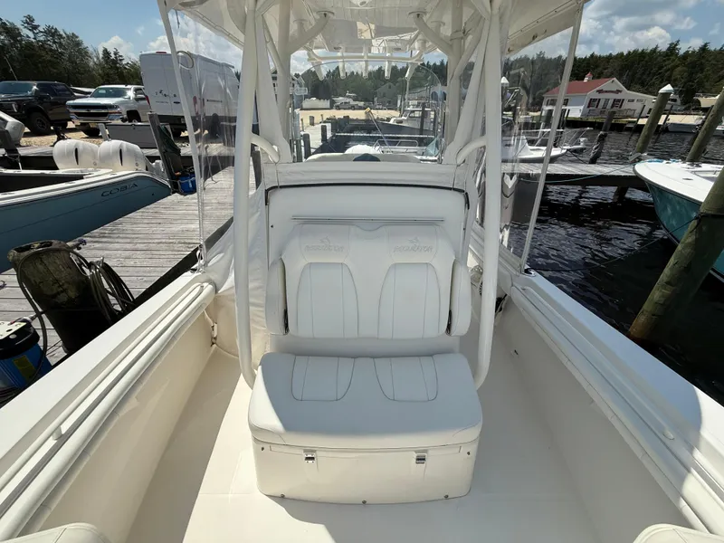 Slide: The Image of 2018 Regulator 23 boat interior with white seating at a marina dock. - 18