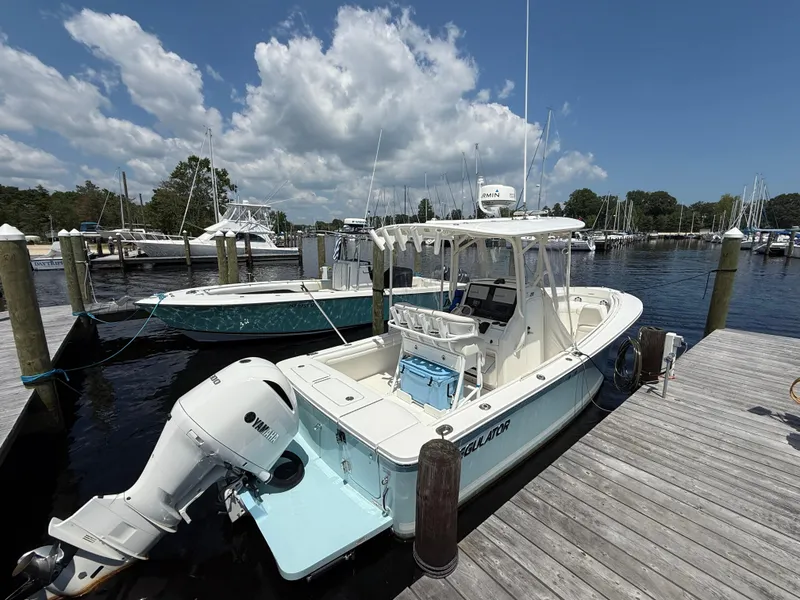 Slide: The Image of 2018 Regulator 23 boat docked at marina under blue sky. - 2