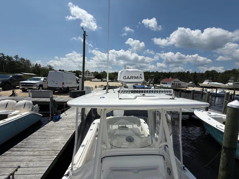 Slide: The Image of 2018 Regulator 23 boat docked at marina with Garmin equipment, under a partly cloudy sky. - 23