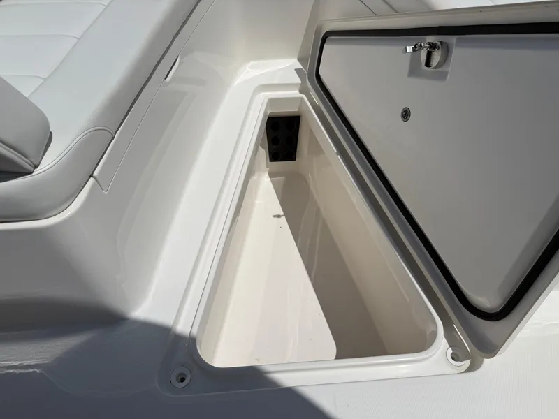 Slide: The Image of Open storage compartment on a 2018 Regulator 23 boat, featuring a cushioned seat. - 25