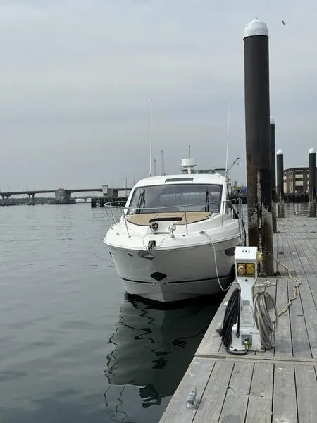 Slide: The Image of 2019 Sea Ray 350 Sundancer Coupe docked at a marina on a cloudy day. - 11
