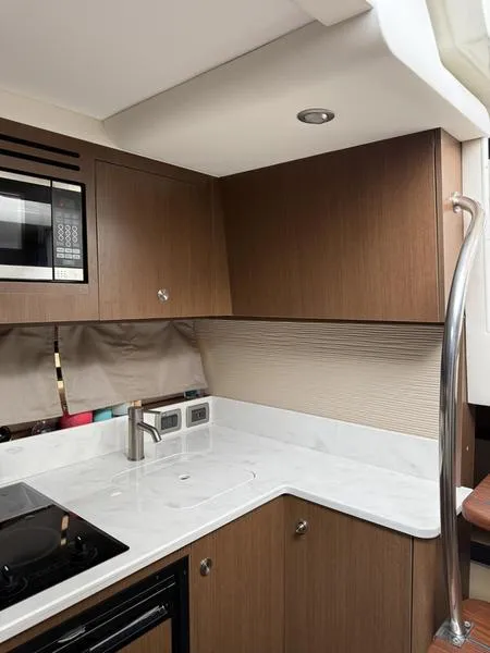 Slide: The Image of Interior of 2019 Sea Ray 350 Sundancer Coupe kitchen with modern appliances and wood cabinetry. - 12