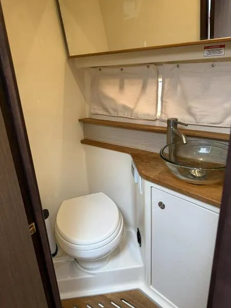 Slide: The Image of 2019 Sea Ray 350 Sundancer Coupe bathroom with modern glass sink and compact toilet. - 13