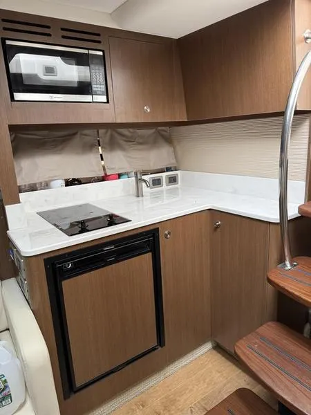 Slide: The Image of 2019 Sea Ray 350 Sundancer Coupe kitchen with microwave, stove, and compact fridge. - 18