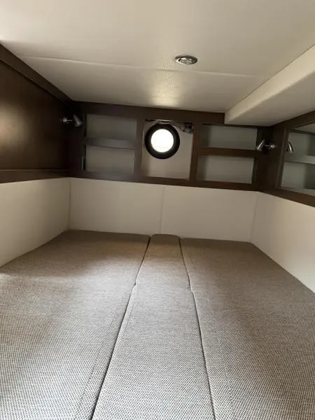 Slide: The Image of 2019 Sea Ray 350 Sundancer Coupe cabin interior with bed and porthole window. - 19