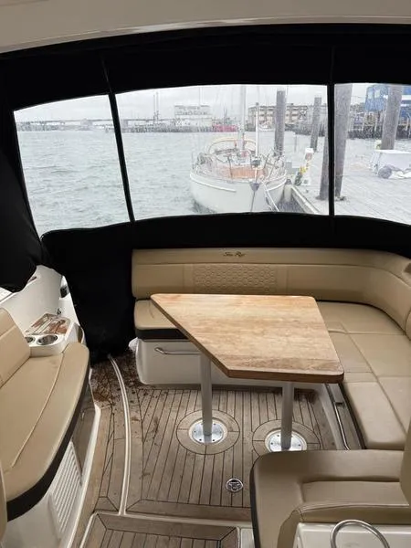 Slide: The Image of 2019 Sea Ray 350 Sundancer Coupe interior with seating and table, docked at marina. - 23