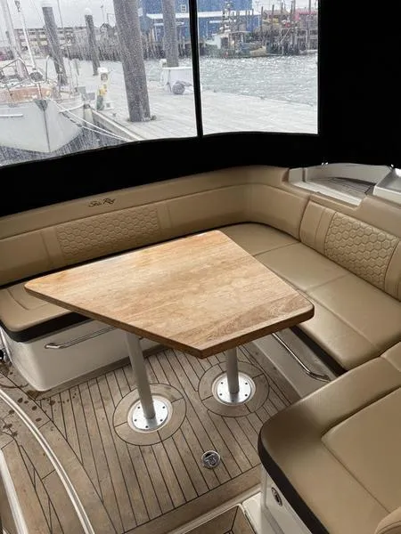 Slide: The Image of 2019 Sea Ray 350 Sundancer Coupe interior with beige seating and wooden table. - 26