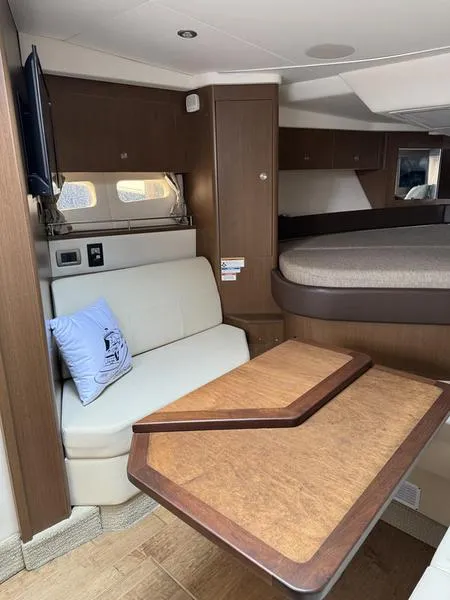 Slide: The Image of 2019 Sea Ray 350 Sundancer Coupe interior with seating, table, and bed. - 27
