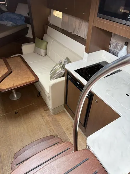 Slide: The Image of 2019 Sea Ray 350 Sundancer Coupe interior with kitchen, sofa, and wooden table. - 29