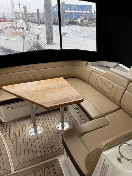 Slide: The Image of 2019 Sea Ray 350 Sundancer Coupe interior with beige seating and wooden table. - 31