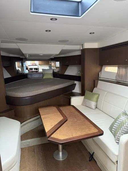 Slide: The Image of 2019 Sea Ray 350 Sundancer Coupe interior with modern seating, table, and bed. - 32