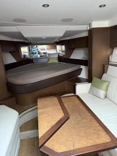 Slide: The Image of 2019 Sea Ray 350 Sundancer Coupe interior with bed, seating, and wooden table. - 33