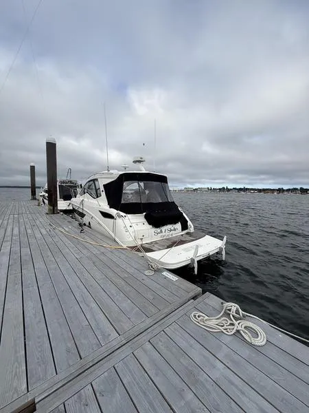 Slide: The Image of 2019 Sea Ray 350 Sundancer Coupe docked at a marina under cloudy skies. - 4