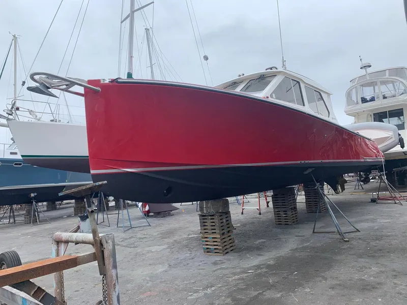Slide: The Image of Red 2002 True North 38 boat on dry dock, supported by stands, with overcast sky. - 28