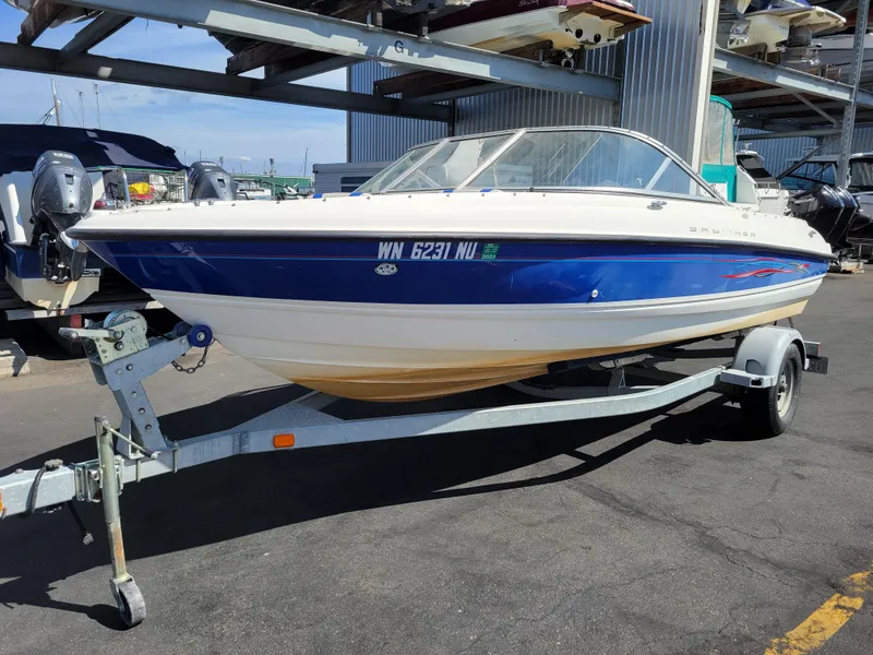 The Image of 2006 Bayliner 195 boat on trailer, blue and white design, parked in marina. - 1
