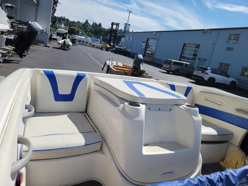 Slide: The Image of 2006 Bayliner 195 boat interior with blue and white seating, docked near a marina. - 11