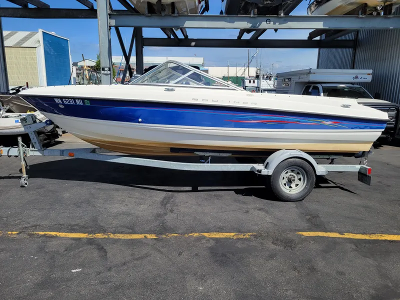 Slide: The Image of 2006 Bayliner 195 boat on trailer, blue and white design, parked outdoors. - 2