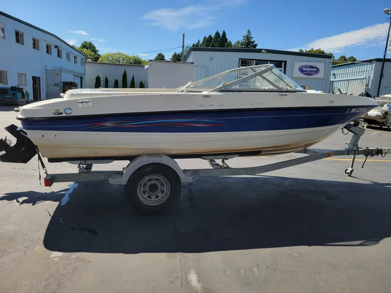 Slide: The Image of 2006 Bayliner 195 boat on trailer, parked outdoors near industrial buildings. - 5