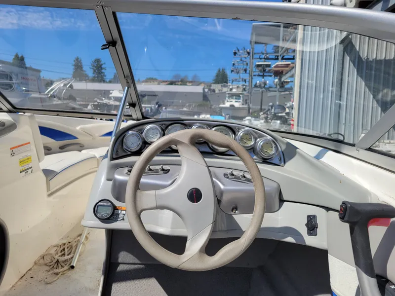 Slide: The Image of 2006 Bayliner 195 boat dashboard with steering wheel and gauges under clear blue sky. - 9