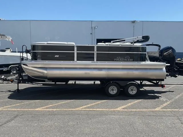 Slide: The Image of 2025 Sun Tracker Party Barge 20 DLX pontoon boat on trailer, parked outdoors. - 4