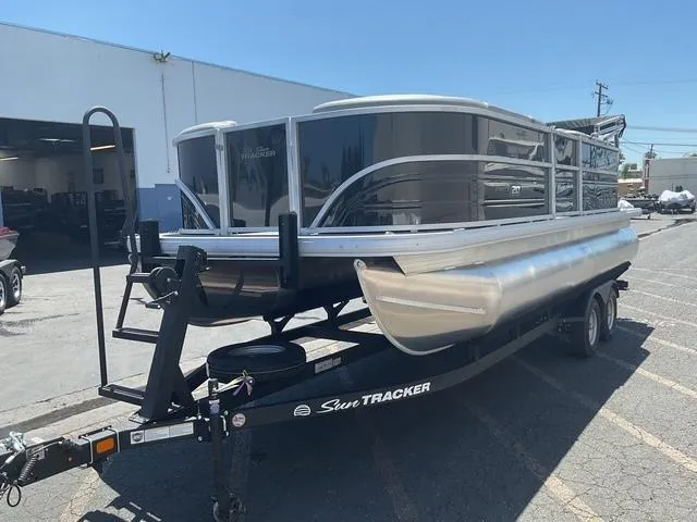 Slide: The Image of 2025 Sun Tracker Party Barge 20 DLX pontoon boat on trailer in parking lot. - 5