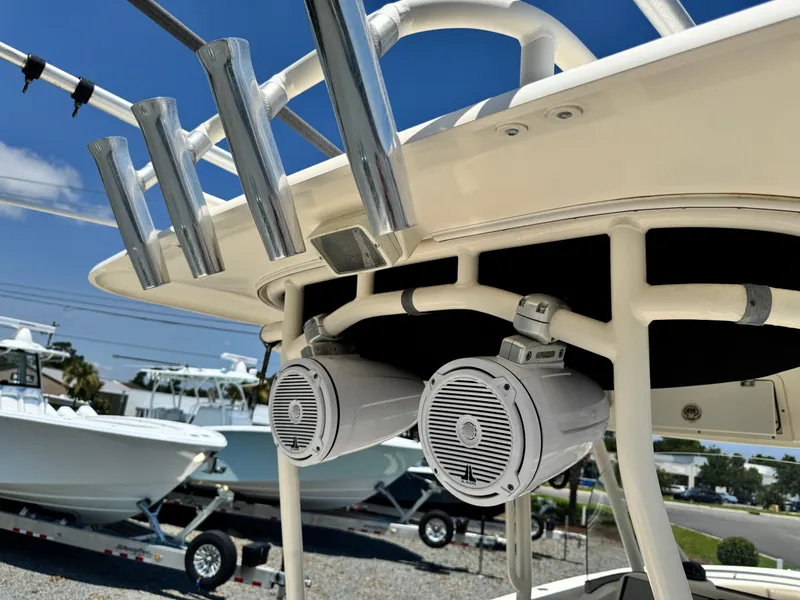 Slide: The Image of 2010 Pursuit C 280 Center Console with mounted speakers and rod holders, docked under clear skies. - 24