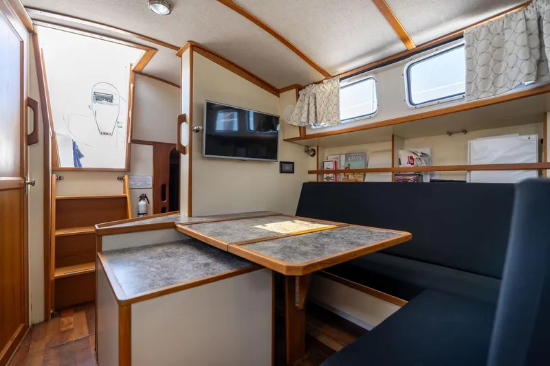 Slide: The Image of 1978 Cascade High Side boat interior with dining area, TV, and wooden accents. - 11