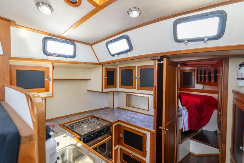 Slide: The Image of 1978 Cascade High Side boat interior with kitchen, wooden cabinets, and cozy sleeping area. - 18